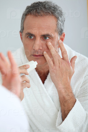 Portrait of mature man applying moisturizer on his face