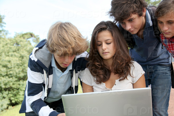 Teenagers sitting outside with laptop computer