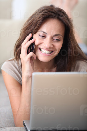 Woman on couch with laptop computer and telephone