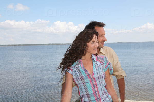 Closeup of loving couple standing on a pontoon by a lake