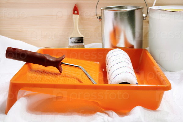 Conceptual photo with paint and roller, selective focus on handle of nearest tool, stock photo