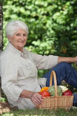 elderly woman in garden with basket of vegetables