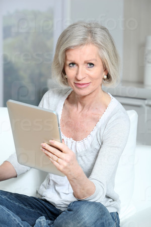 Closeup of senior woman sitting on sofa with electronic pad