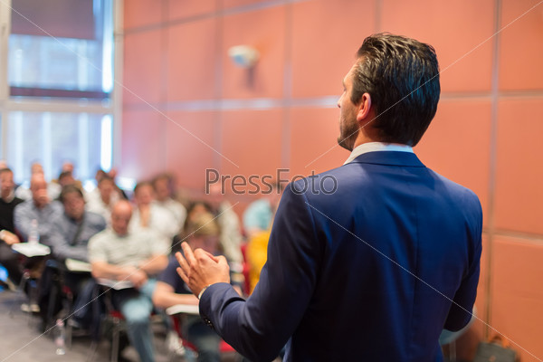 Speaker at Business Conference with Public Presentations. Audience at the conference hall. Entrepreneurship club. Rear view. Horisontal composition. Background blur, stock photo