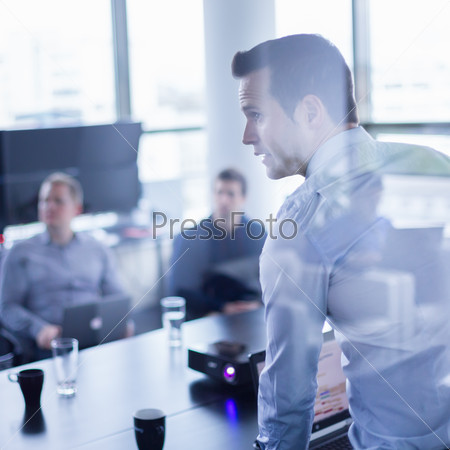 Business man making a presentation at office. Business executive delivering a presentation to his colleagues during meeting or in-house business training, explaining business plans to his employees.