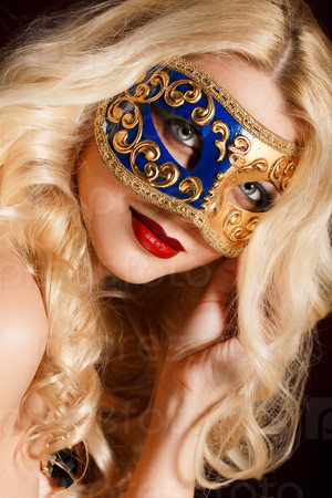 Portrait of a beautiful young blond woman with theatrical mask on his face on a dark background