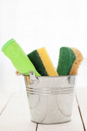 Cleaning sponges in a silver pail on a white wooden table