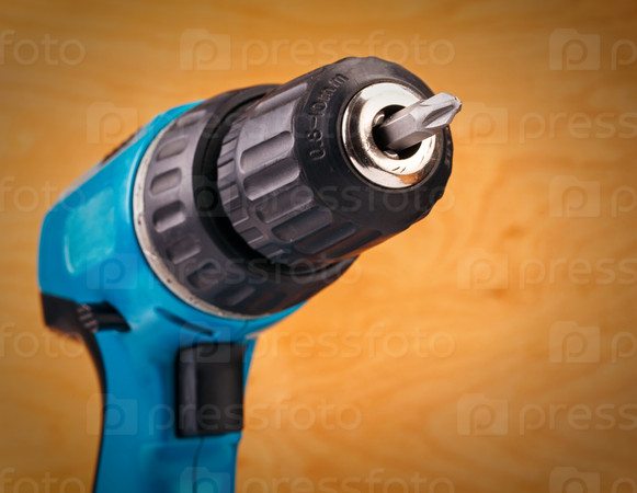 electric drill with drill bit on a wooden background