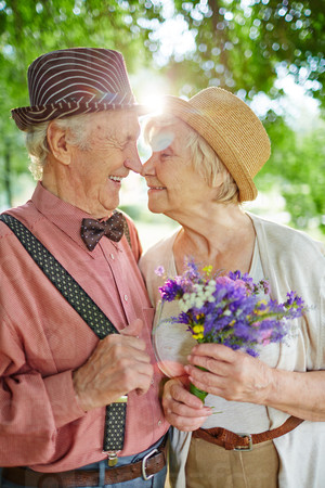 Amorous seniors touching by their noses in natural environment