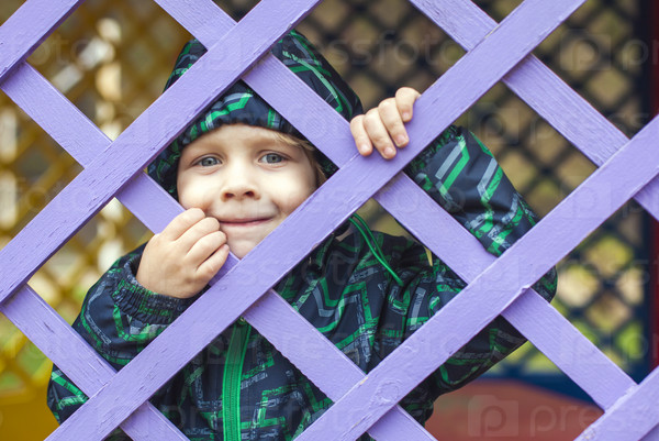 little baby boy looking through blue fence