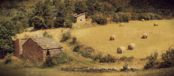 Landscape with harvested bales of straw in field and stone house, Spain