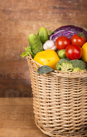 Fruits and vegetables in the basket on wooden background