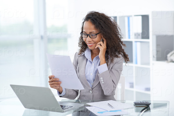 Female business executive with a document in her hand talking on the phone