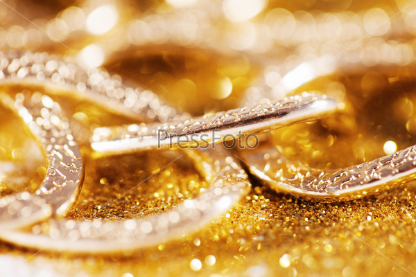Closeup of yellow gold luxury jewelery on golden glitter