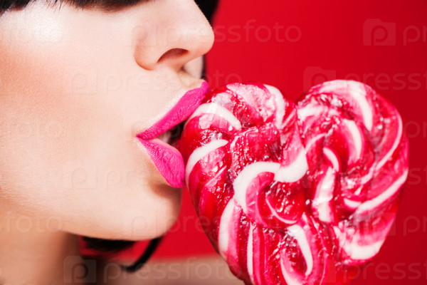 Closeup photo of a beautiful sexy red lips with lollipop on red