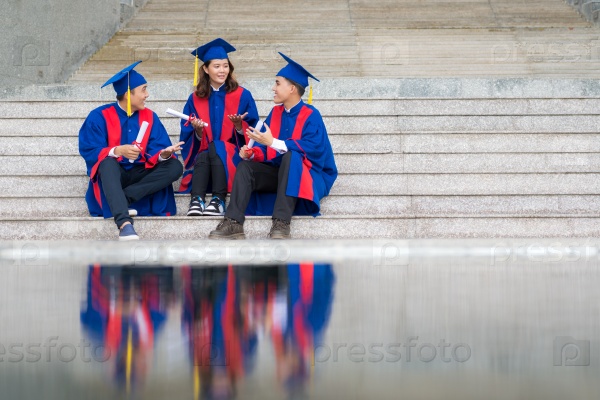 Chatting graduates sitting on the stairs of university