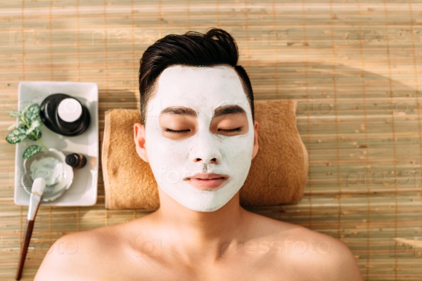 Asian young man in spa salon with facial mask on his face