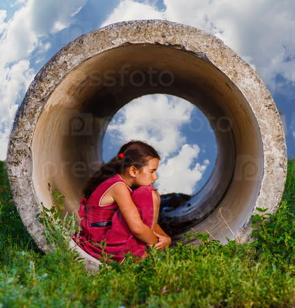 Homeless teenager girl sits on his haunches in the concrete pipe ring ill agoraphobia sad picture on the street psychology