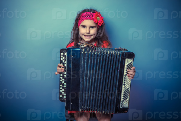 a girl of seven European appearance brunette in a bright dress plays accordion on gray background, music, talent retro photo effect