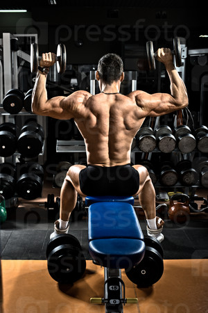 very brawny guy bodybuilder,  execute exercise with  dumbbells, on deltoid muscle shoulder