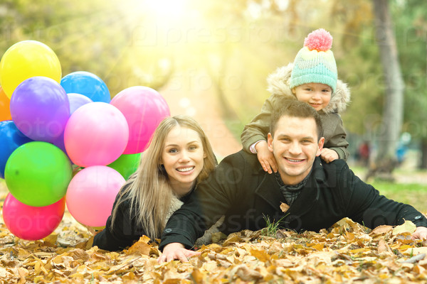 Happy family with little child and air-balloons, outing in autumn park, stock photo