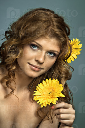 the very  pretty red-haired blue eyed young woman  with yellow flower,  smile , vertical close up portrait