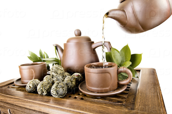 horizontal photo, of the clay teapot tea flow in  cup on white background,  isolated, tea ceremony