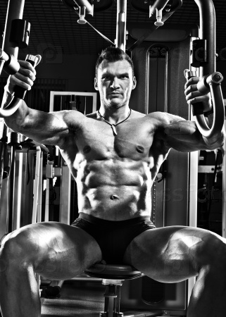 very brawny guy bodybuilder ,  execute exercise  on gym apparatus Butterfly Machine, in gym. Black-and-white photo