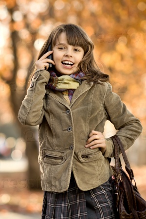 vertical photo,  stylish beautiful little girl hold  mobile phone and gladness talk