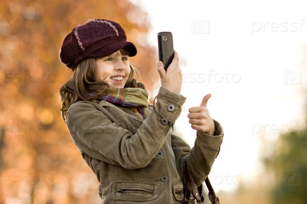 happy beautiful little girl take a photograph on mobile phone, autumnal portrait