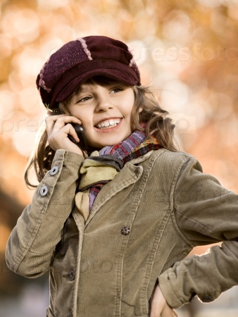 Vertical photo, stylish beautiful little girl hold mobile phone and gladness talk, stock photo