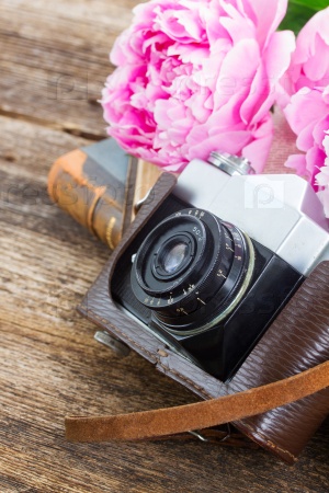 old  photo camera with books and pink peony flowers