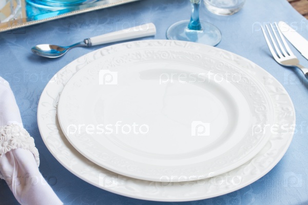 Tableware - set of plates, cups and utencils on blue tablecloth