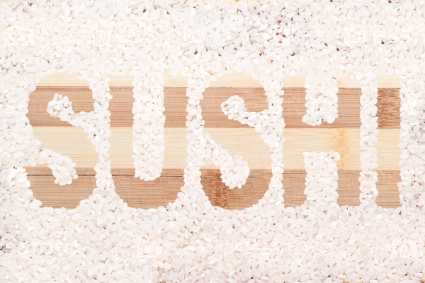 Rice grain. Word sushi written on wooden cutting board. For background