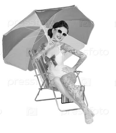 Pin-up girl tattoos happy resting on the beach stretching in the beach chair