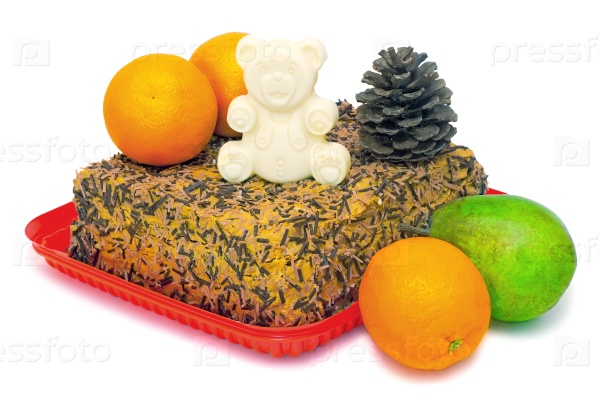 Delicious chocolate cake with a figurine of a bear white chocolate, pine cones. Nearby are the fruits: oranges, pear. Presented on a white background. and fruit.