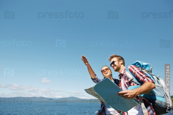 Cheerful hikers with map choosing route for travel