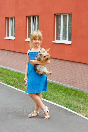 Girl 6 years with Yorkshire terrier in her arms near a high-rise building