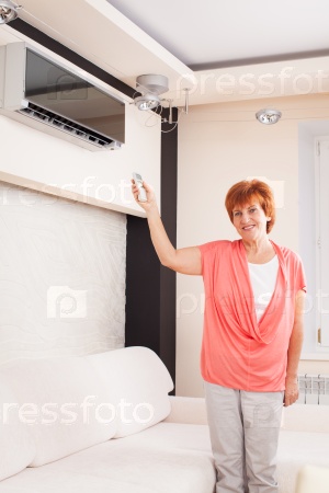 Woman holding a remote control air conditioner