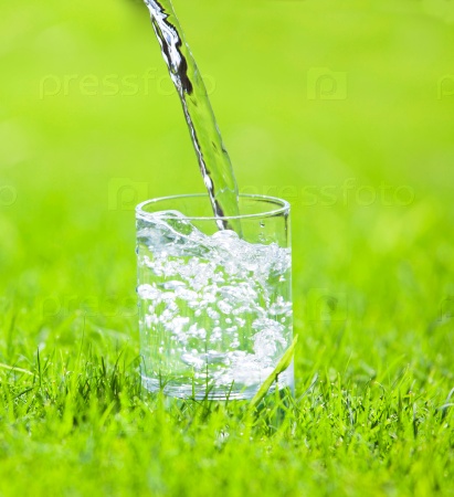 Water poured into glass. Pure water on green background