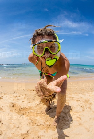 Woman on beach vacation holidays with snorkel lying in sand with snorkeling mask and fins smiling happy enjoying the sun on sunny summer day.