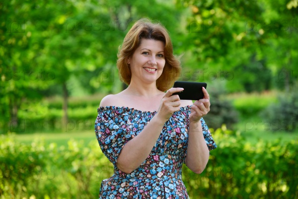 woman with a cell phone in nature in the summer