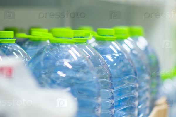 Бутылки пресной воды с зеленым чашки в супермаркете