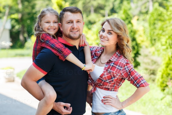 Young happy family of three having fun together outdoor. Pretty little daughter. Parents and girl look happy and smile. Happiness and harmony in family life. Family fun outside.