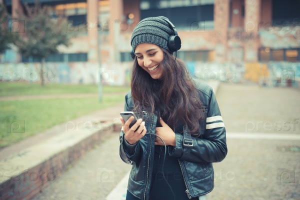 young beautiful brunette woman listening music with headphones in the city