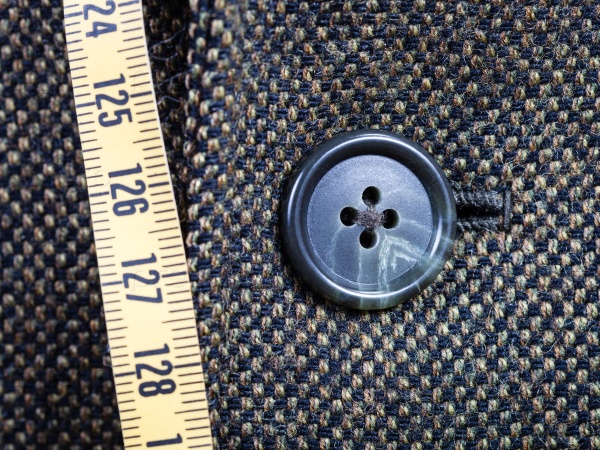Measuring tape and buttoned button on tweed jacket