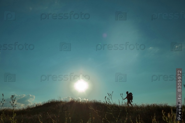 Young caucasian man with backpack walking on a green meadow