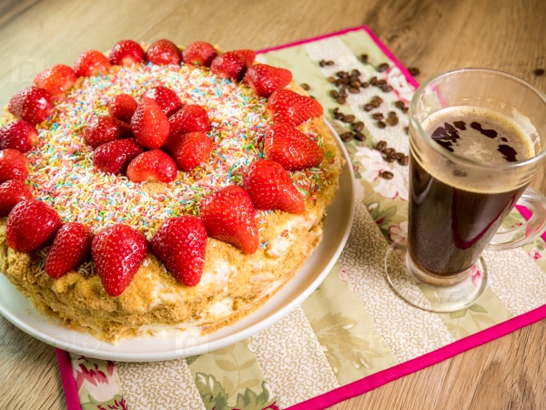 Honey cake with strawberry on top and coffee table