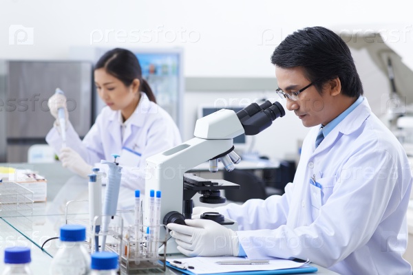 Asian researcher working with modern microscope in laboratory