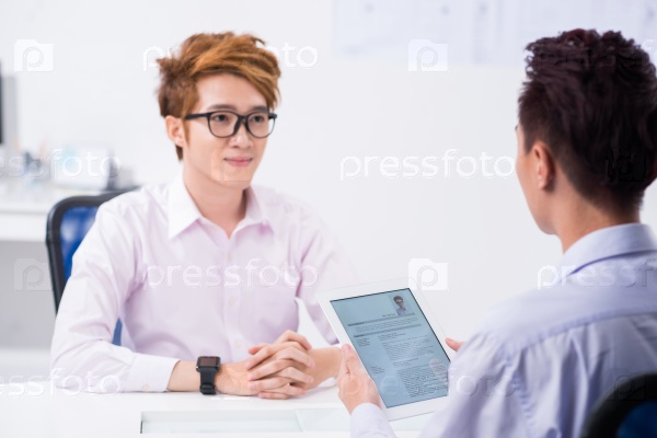HR manager using digital tablet while interviewing applicant